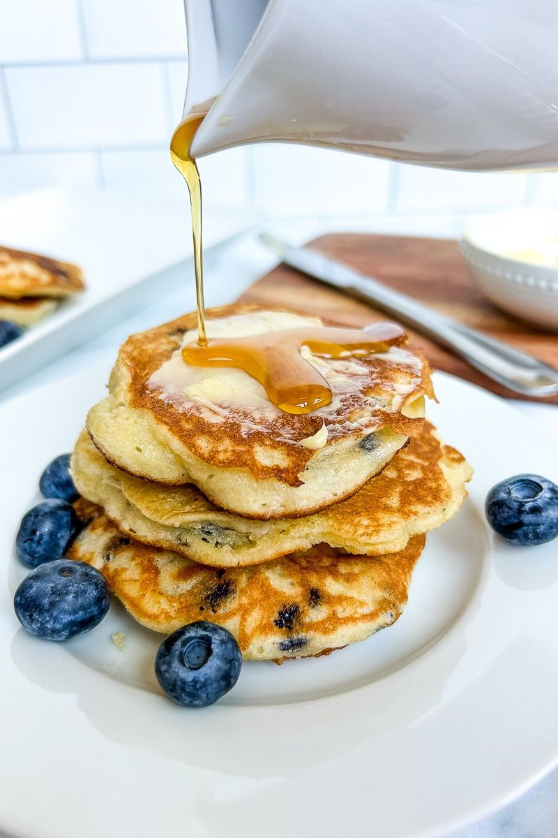Stack of pancakes with blueberries and with a syrup on top.