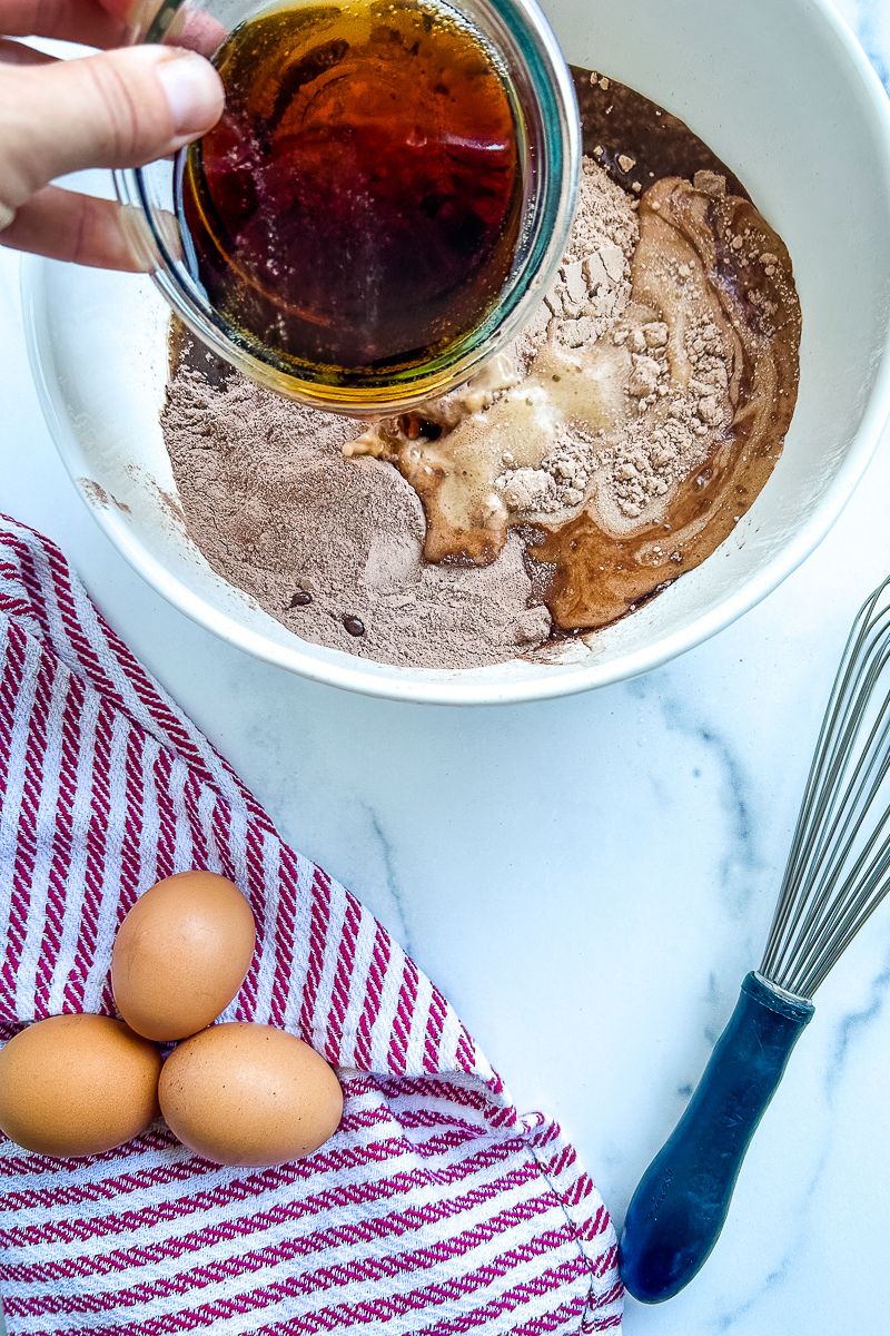 Raw ingredients for a cake batter in a mixing bowl, and 3 pieces of eggs, and whisk.