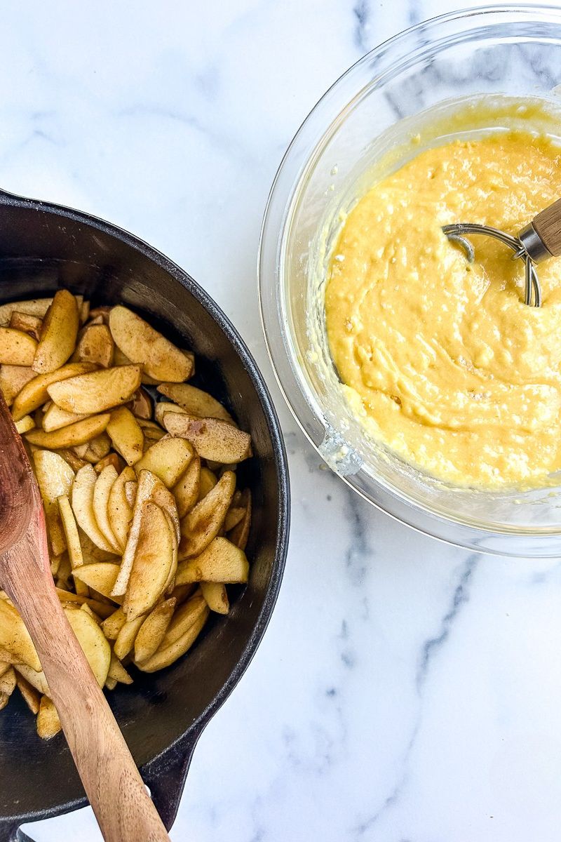 Apple mixture in a Dutch oven and a bowl or cake batter in a glass bowl.