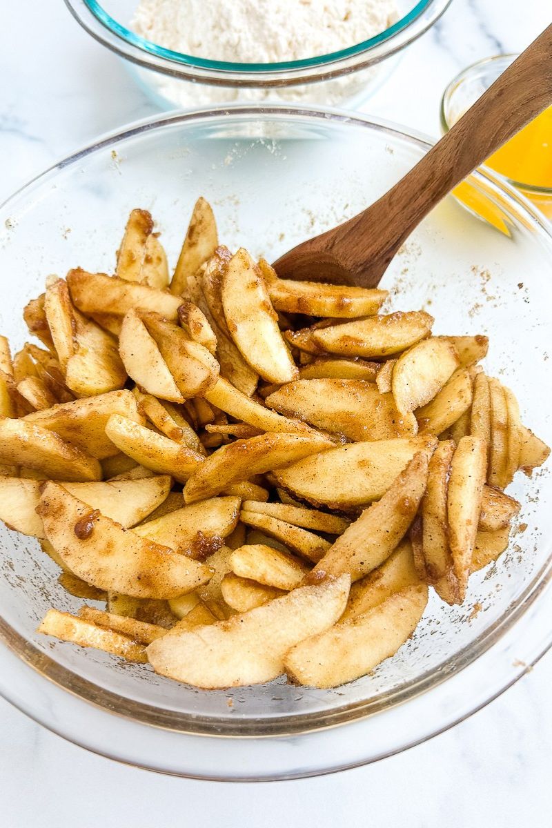 A mixture of apples with cinnamon in a glass bowl.