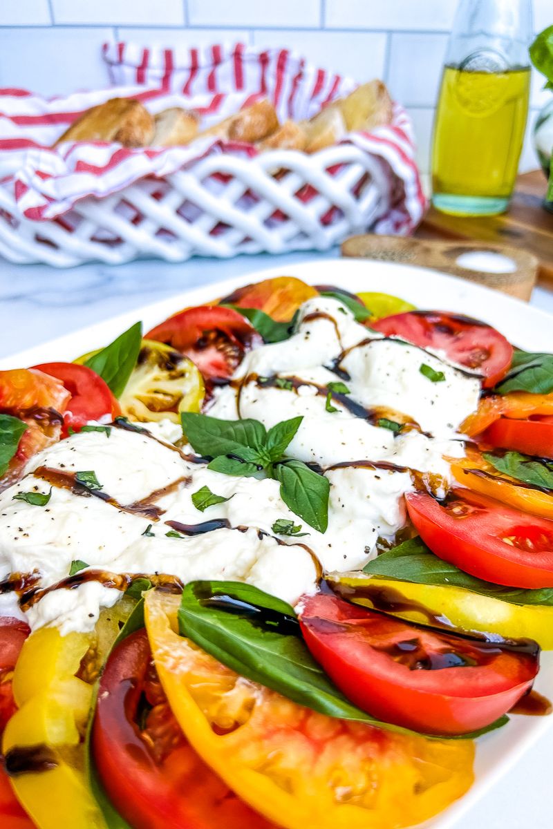 Burrata caprese on a white serving plate.