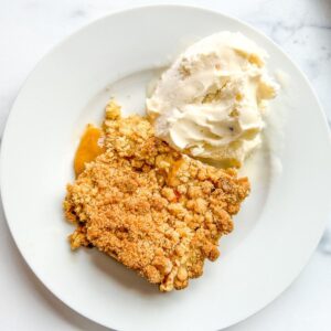 A plate of peach cobbler with ice cream.