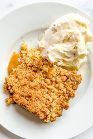 A plate of peach cobbler with ice cream.