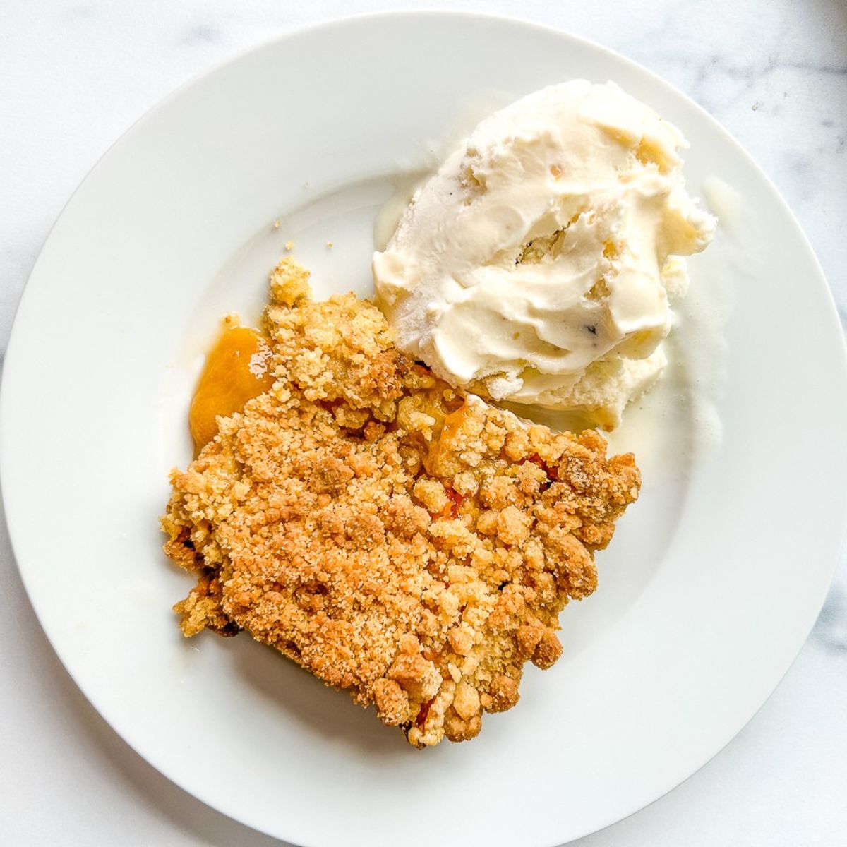 A plate of peach cobbler with ice cream.