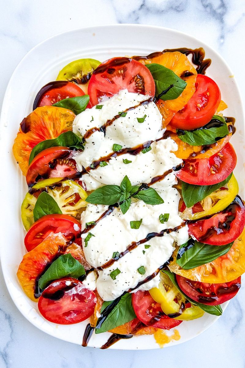 Burrata caprese on a white serving plate.