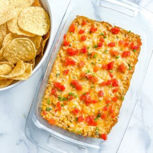 A platter or corn dip and a bowl of chips.