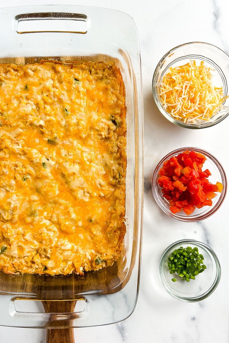 Corn dip in a baking pan with 3 bowls of toppings.