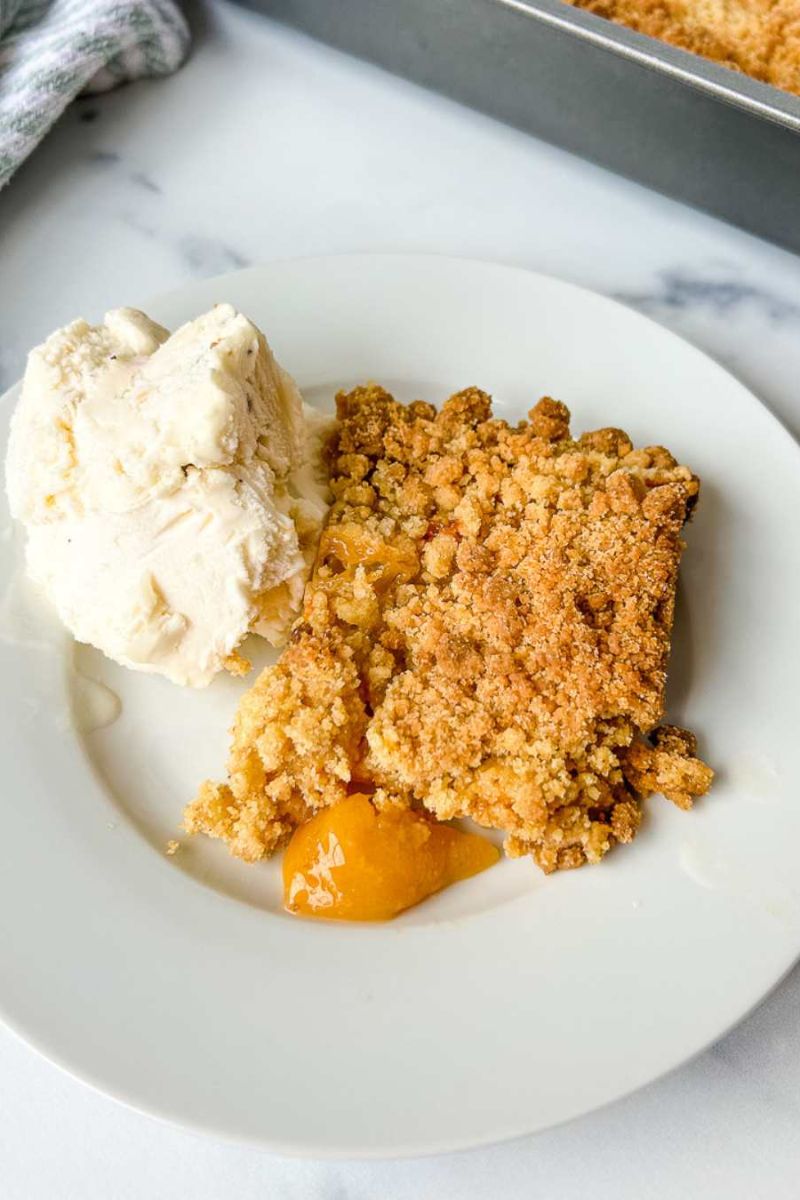 A plate of peach cobbler with ice cream.