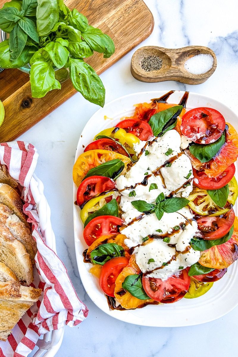 Burrata caprese on a white serving plate.