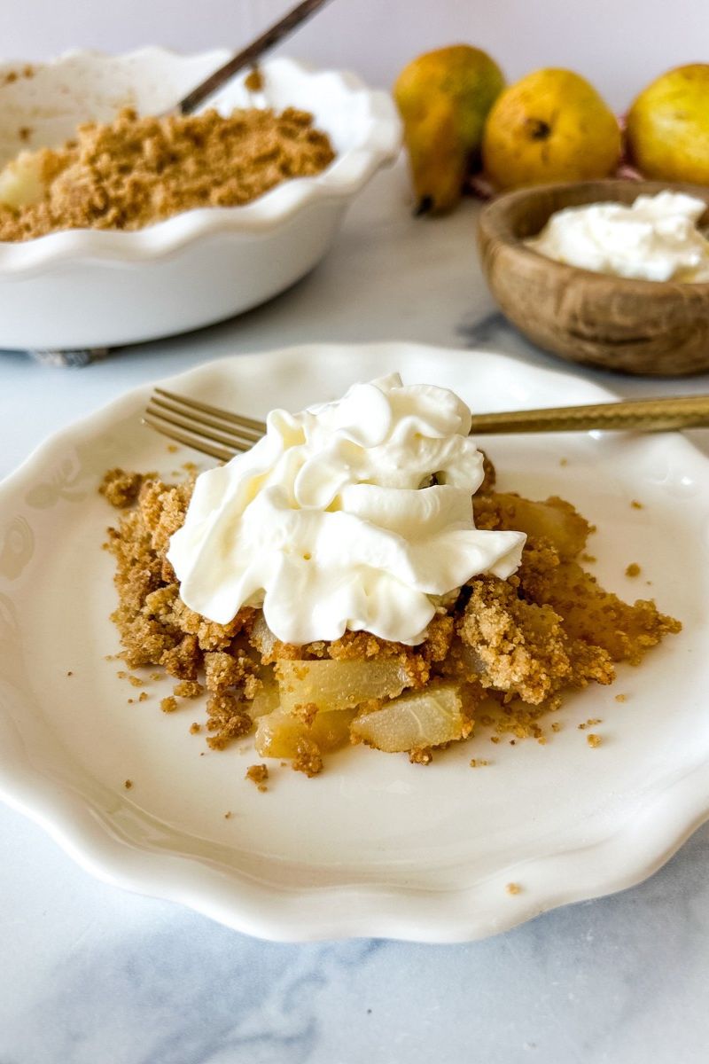 A plate of pear crumble topped with cream.