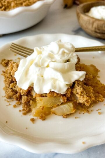 A plate of pear crumble topped with cream.