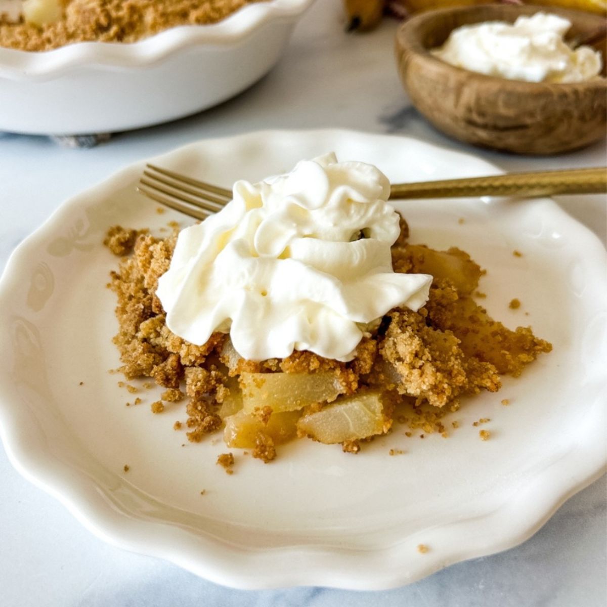 A plate of pear crumble topped with cream.