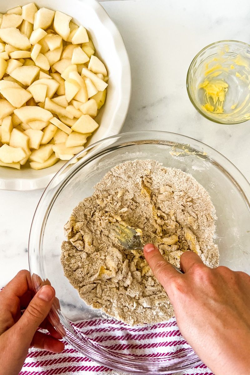 Apples in a pie pan and a bowl of mixture for the crumble.