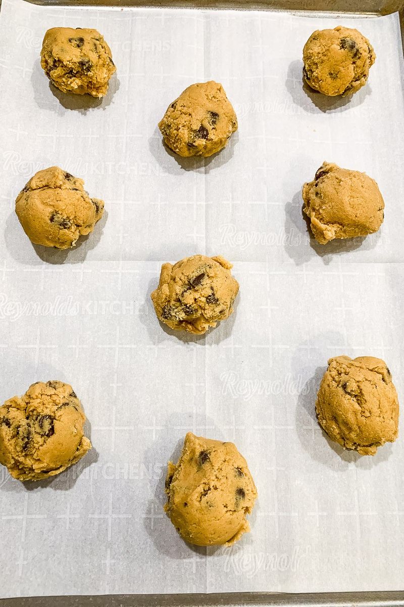 Cookie dough balls on a baking sheet with parchment paper.