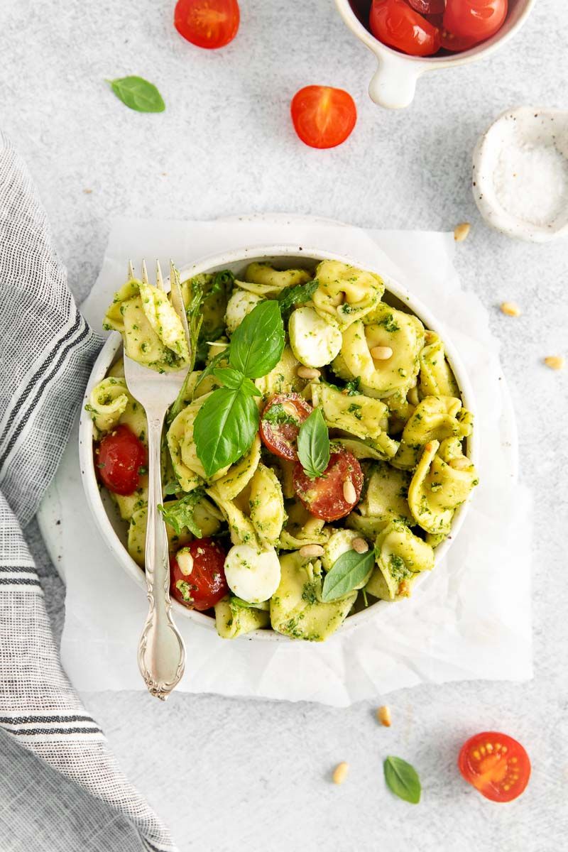 A bowl of pesto with tortellini with fork.
