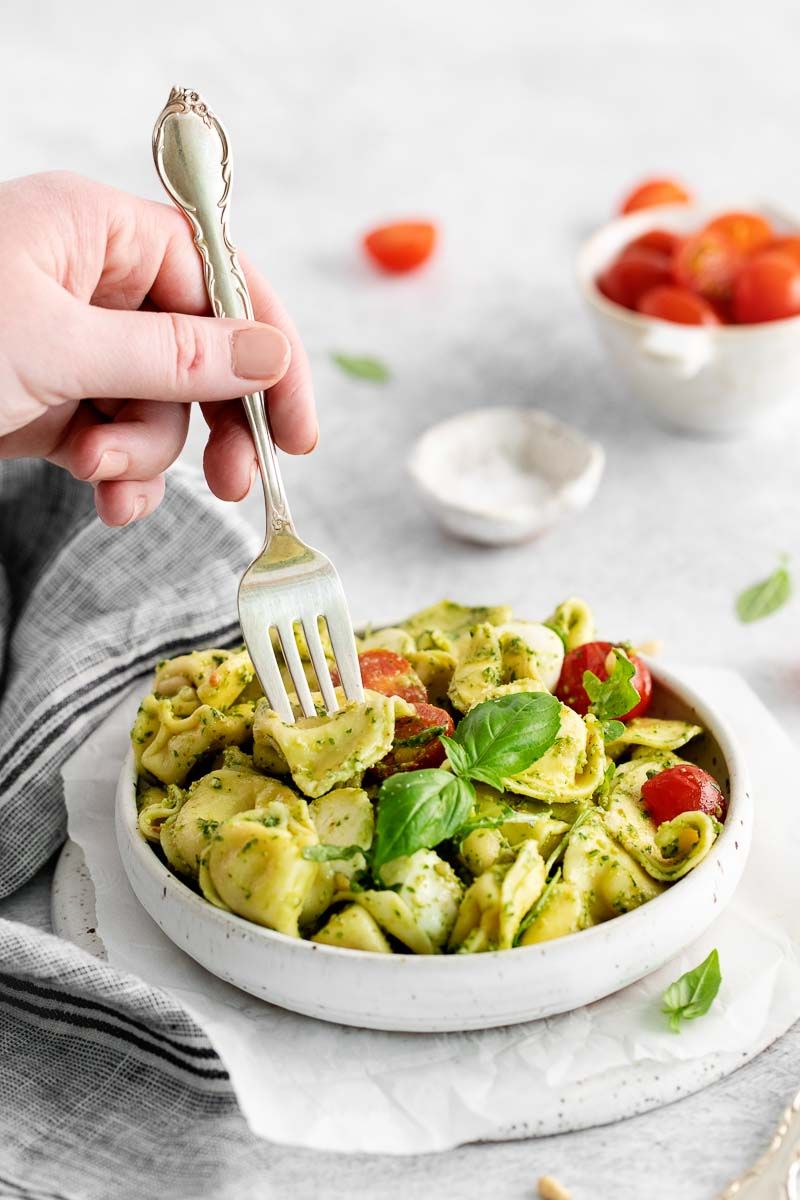 A bowl of pesto with tortellini with fork.