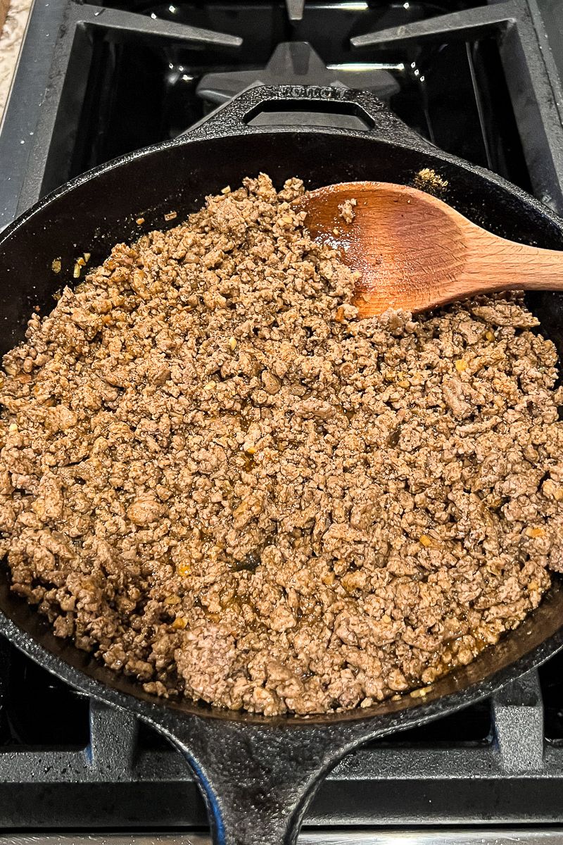 A skillet of ground beef with wooden spoon.