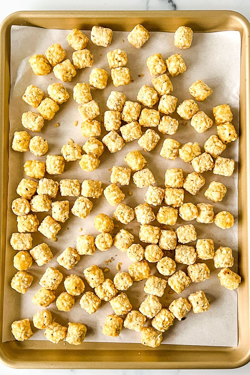 A pan of tater tots with parchment paper.