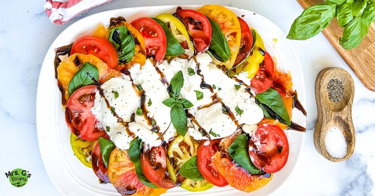 Burrata caprese on a white serving plate.
