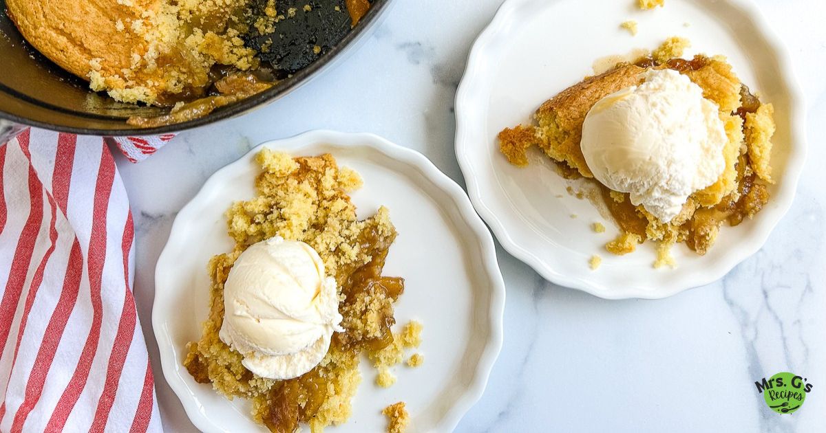 Two servings of apple cobbler with vanilla ice cream on a white plate.