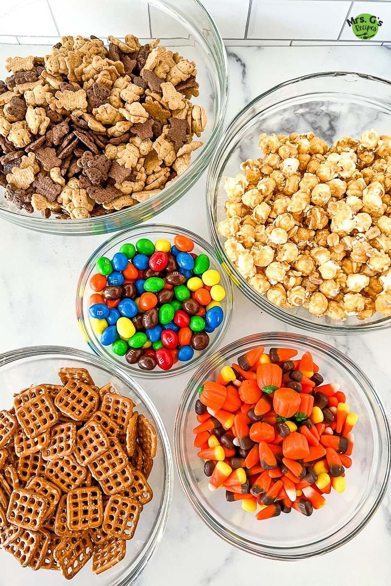 5 bowls of ingredients for Halloween snack mix.