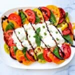 Burrata caprese on a white serving plate.