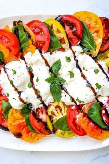 Burrata caprese on a white serving plate.