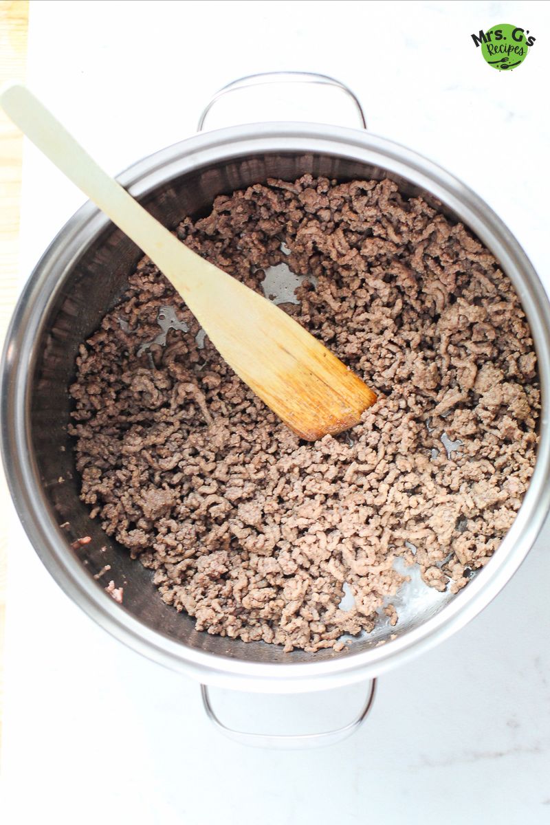 A pan with ground meat with wooden ladle.