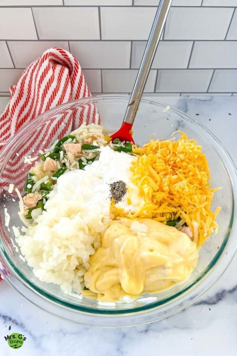 A bowl of raw ingredients for chicken and hash brown casserole.