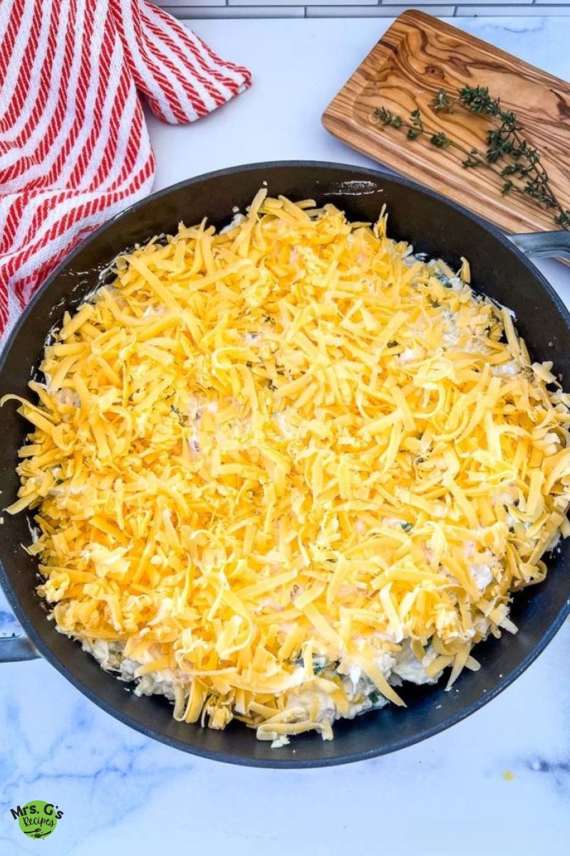 A skillet pan of unbaked chicken and hash brown casserole.