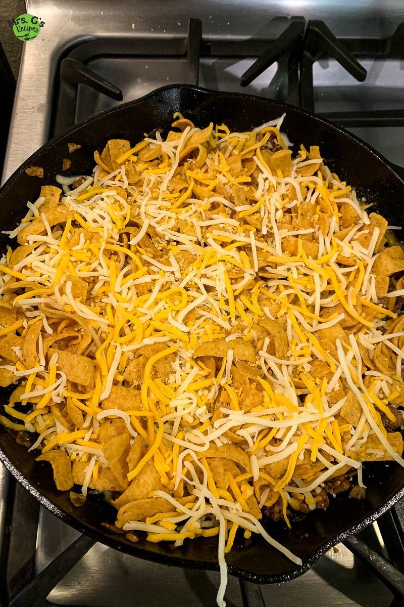 A skillet of frito with cheese on top.