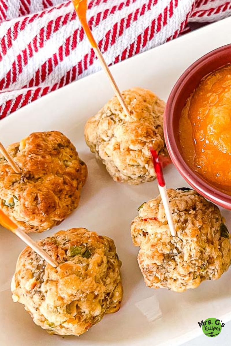 Sausage balls on a platter with a bowl of sauce.