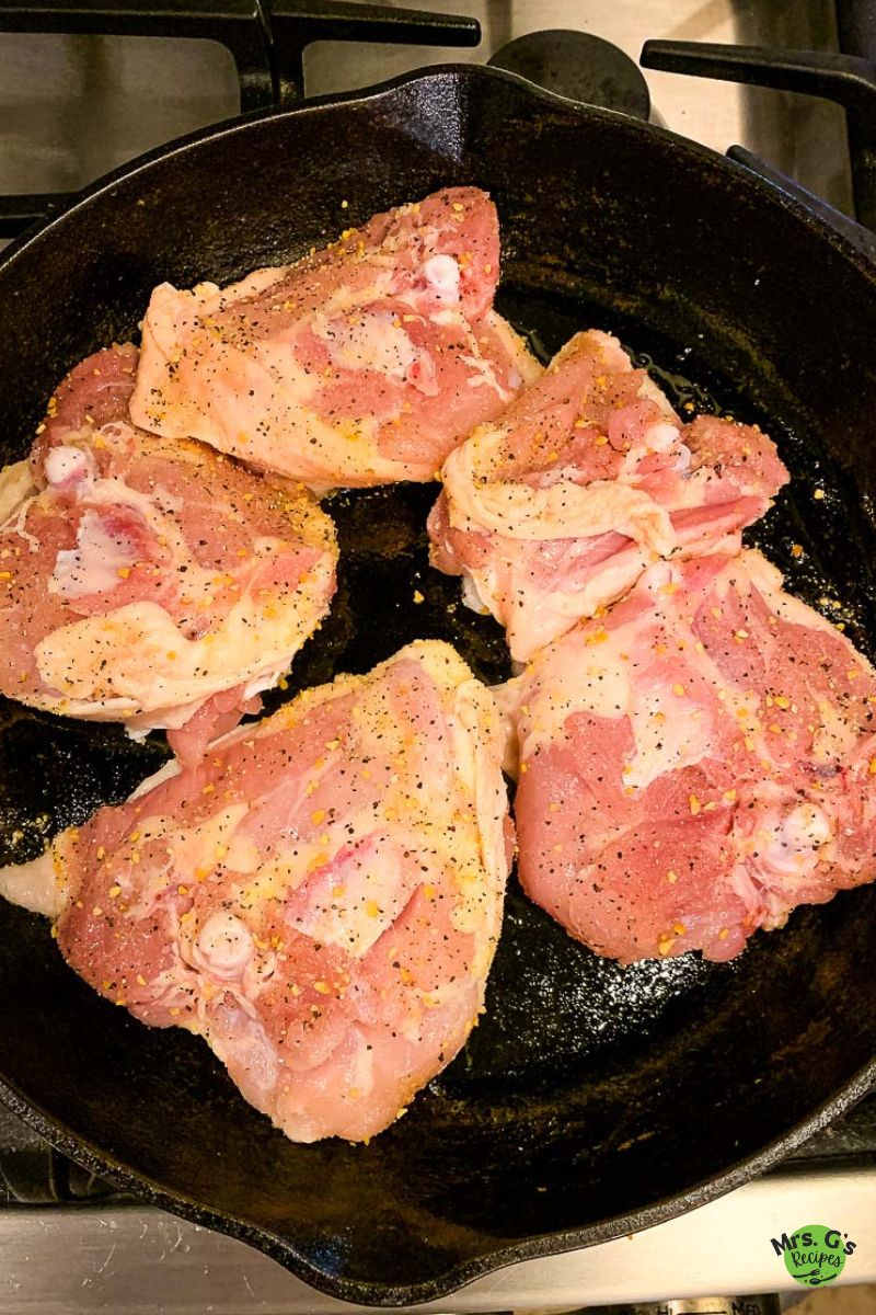 a skillet of chicken thighs sprinkled with salt and pepper.