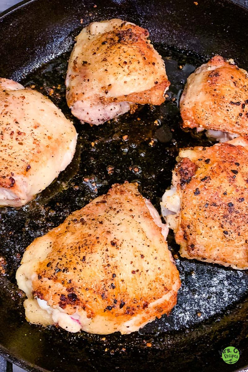 a skillet of golden chicken thighs.