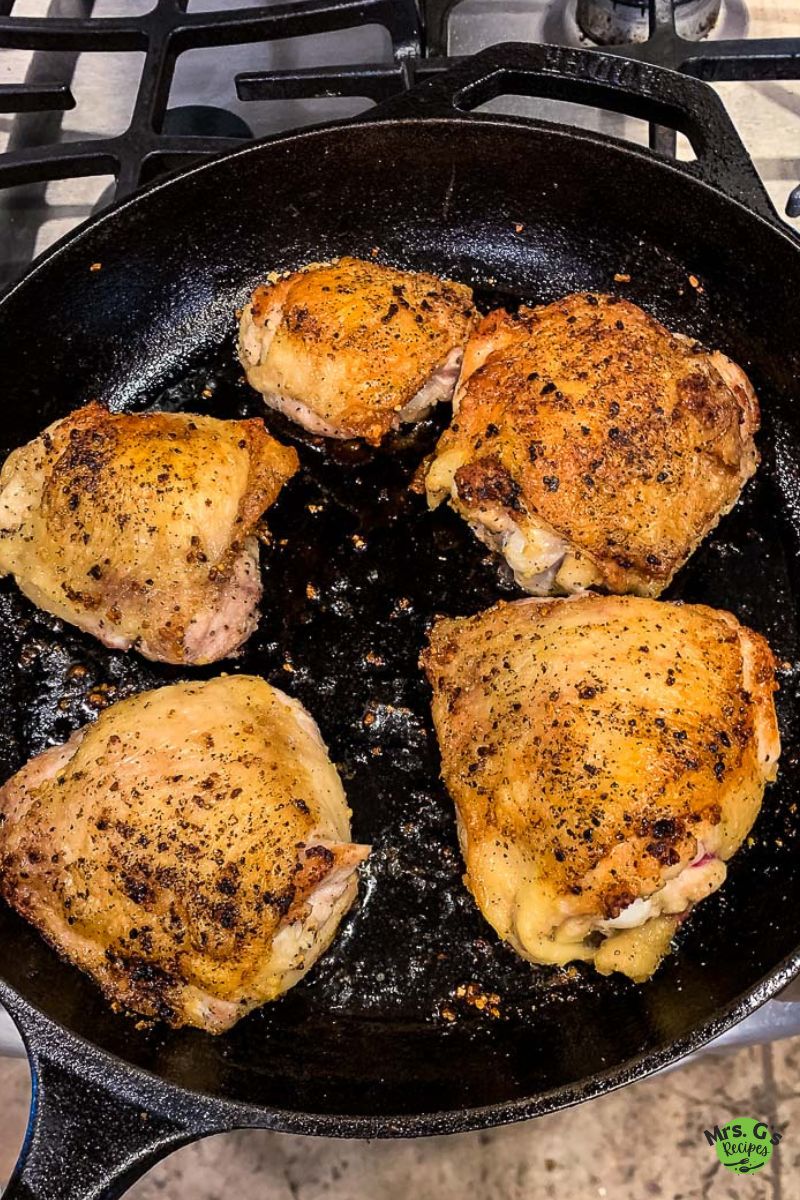 a skillet of golden chicken thighs.