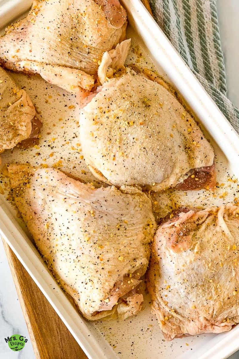 a plate of chicken thighs sprinkled with garlic salt and pepper.