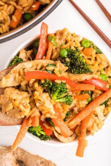 a spoonful of fried rice with veggies and chicken.