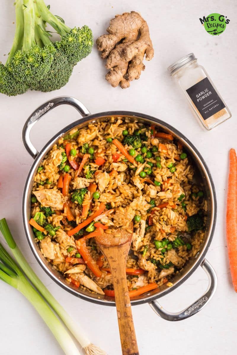 A pan of fried rice with veggies and chicken.