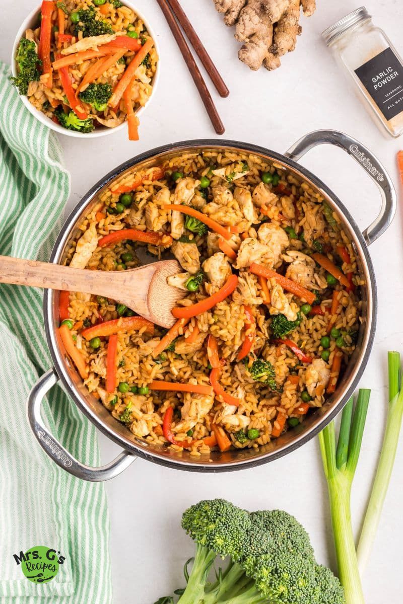 A pan of fried rice with veggies and chicken.