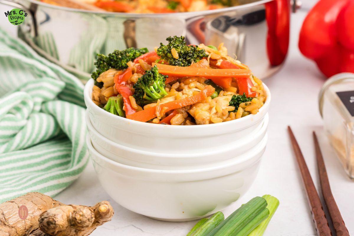 A bowl of fried rice with veggies and chicken.