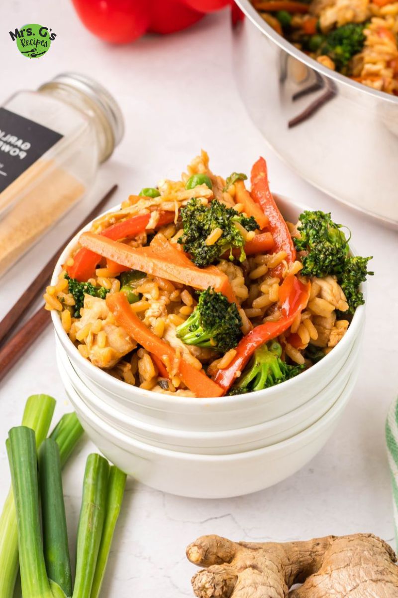 A bowl of fried rice with veggies and chicken.