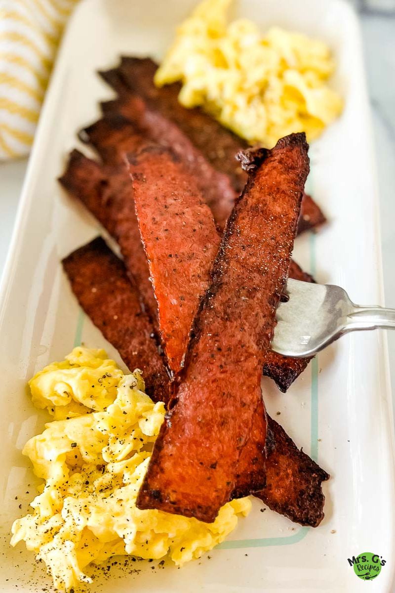 a plate of turkey bacon strips with egg.