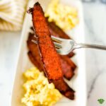 an image of turkey bacon strip with a plate of bacon and egg at the background.