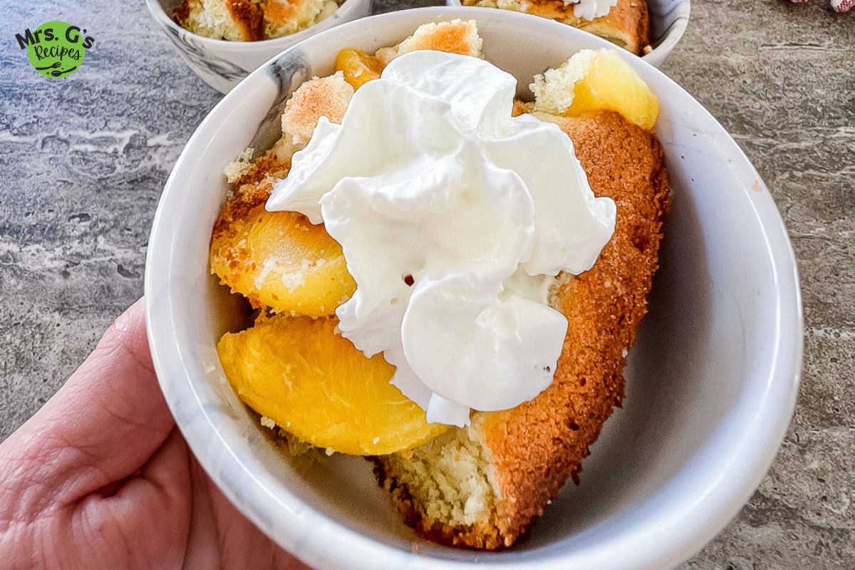 Extreme close up of peach dessert topped with whipped cream.