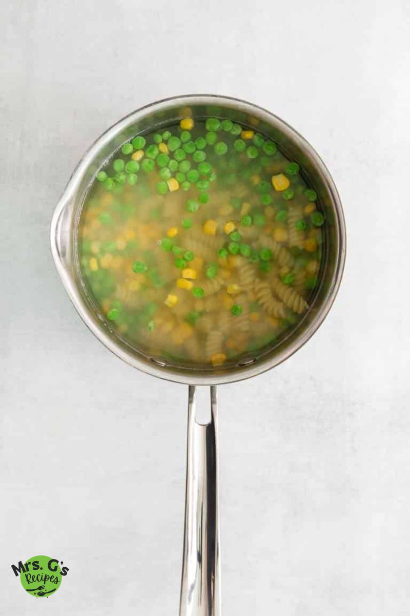 cooking the peas, corn and fusilli pasta in a pot.