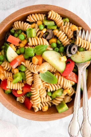 Zesty Italian Pasta Salad and silverwares on a wood bowl.